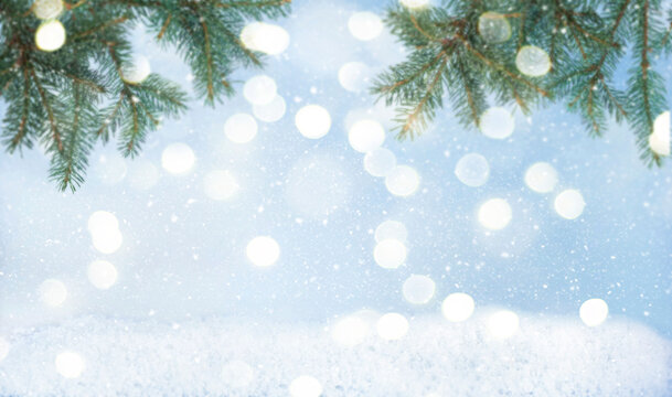 Defocused branches of fir on snowy defocused background with soft golden bokeh. Christmas stock photo background