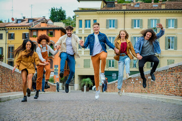 Fototapeta premium Multiethnic group of crazy young people having fun walking and jumping in the city street - Lifestyle and friendship concept