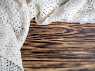 Fototapeta na wymiar Warm cozy white scarf on a wooden background. Place for text