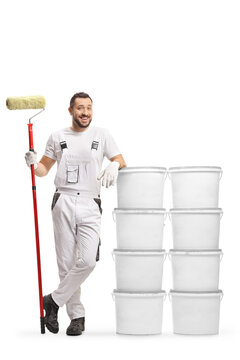 Full length portrait of a house painter leaning on buckets with paint