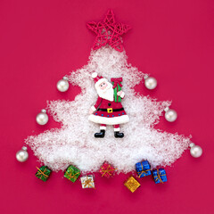 tree with pink background. christmas tree shape with artificial snow with santa claus and gifts