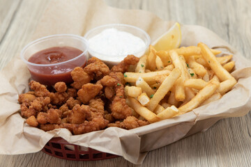 Combination basket full of deep fried clams and a side of french fries with ketchup and dipping...