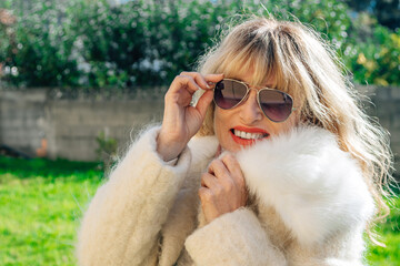 happy woman in coat smiling enthusiastically outdoors