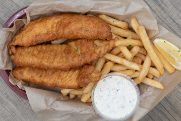 Overhead view of crispy order of breaded fish sticks combined in the basket with french fries to...