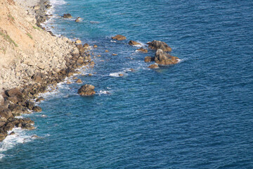 Spiaggia di sassi e rocce con mare fluttuante e scogli