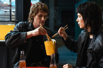 Happy lovely informal couple enjoying food in street cafe
