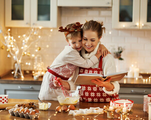 Mother and little son reading recipe book while making dough for christmas gingerbread cookies
