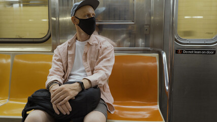 Man uses medical face mask, sits alone in metro carriage, commutes to work by public transport, avoids covid-19, uses equipment for staying safe during coronavirus pandemic. Health care concept
