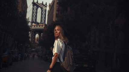 Fashion video of pretty woman near the Brooklyn Bridge in New York City at Sunrise. Young traveling woman in a hat enjoying American holidays.