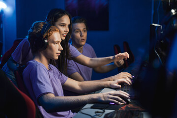 Girl pointing at the screen and discussing with her team while playing at the online games