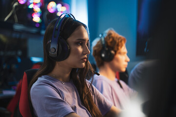 Caucasian smiling woman professional gamer playing in online video game with headphones