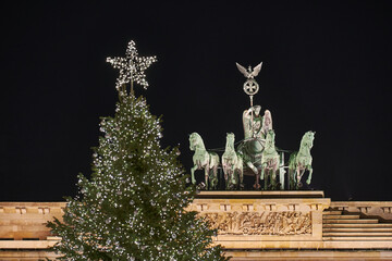 Germany Berlin, Christmas tree in front of illuminated Brandenburg Gate in Berlin City in the evening with dark sky , close up 