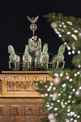 Germany Berlin, Christmas tree in front of illuminated Brandenburg Gate in Berlin City in the evening with dark sky , close up 