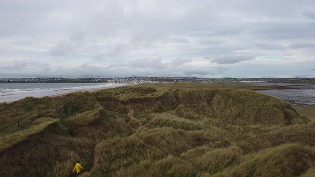 person walking among the dunes of a nature reserve. Tramore Ireland. SandHillls. Un recognizable face.
