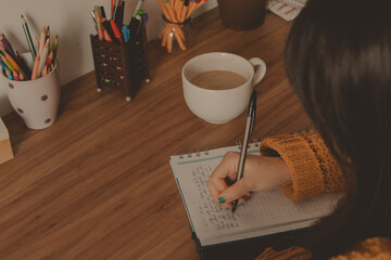 woman writing in a notebook wooden desk