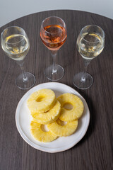 Tasting of white and rose champagne sparkling wine from flute glasses, pairing with fresh ripe pineapple