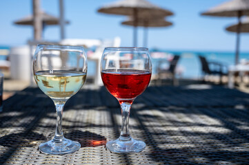 Drinking of cold rose and white wines in lounge bar on sunny sandy beach with blue sea water on background
