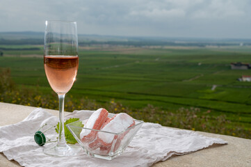 Symbols of Reims, rose brut champagne wine and rose biscuits and view on green pinot noir grand cru vineyards of famous champagne houses in Montagne de Reims near Verzenay, Champagne, France