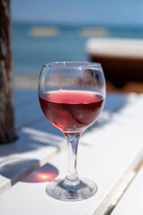 Drinking of cold rose wine in lounge bar on sunny sandy beach with blue sea water on background