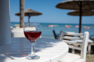 Drinking of cold rose wine in lounge bar on sunny sandy beach with blue sea water on background