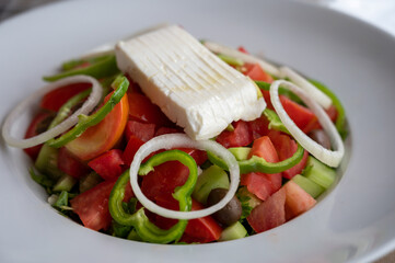 Summer healthy food, vegetable greek salad made with fresh cucumber, tomatoes, onion, feta cheese, green paprika and olives