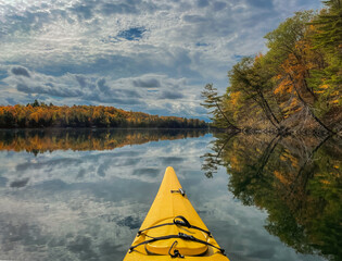 Front of yellow kayak on a calm lake on a beautiful autumn day.