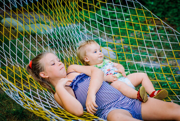 Teenager girls and child having fun in the garden on a hammock