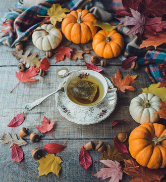 Cup of tea on a wooden table surrounded by autumn decor.