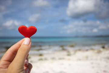 Fototapeta premium Female hand holding small heart on the background of the seascape.