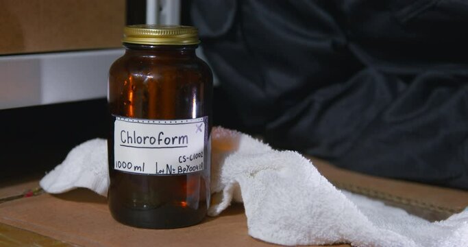 A rag falls on the surface next to a jar of chloroform, close up. Improper use of a chemical solution to commit crimes. Medical substances dangerous to health.