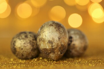 Golden Easter eggs in gold glitter on a gold background with yellow bokeh. Easter festive shiny background