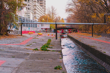 Public space created near a concrete barrier around a river with benches and painted spaces. River...