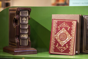 BELGRADE, SERBIA - AUGUST 12, 2021: Selective blur on a Serbian orthodox christian bible and a muslim islam Quran for sale in belgrade,Balkans, where there is a lot of religious cohabitation. ..