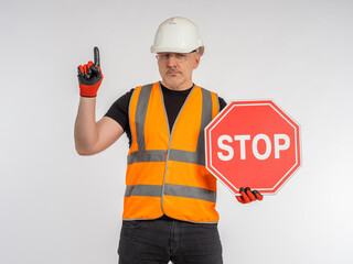 Builder warns of danger. Stop sign in hand of male builder. Concept - approaching place of repair...
