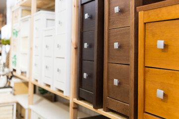 Wooden bedside tables of different colors and sizes with drawers standing on shelves of furniture store