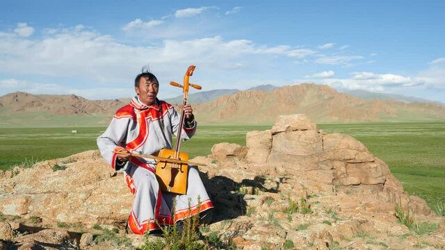Mongolian throat singer performing old traditional folk song in the outdoors near the Altai Mountains, Bayan-Olgii Province, West Mongolia. 