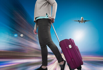 Traveler woman with suitcase awaiting landing aircraft on blurred background
