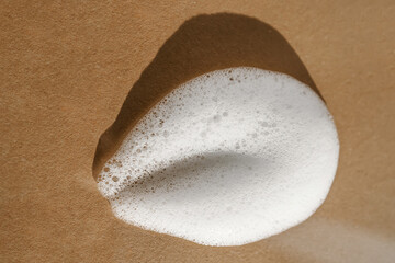 Texture of white foam on a beige background.