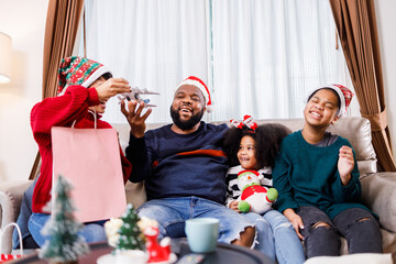 African American family surprised with a gift on Christmas day. Merry Christmas. African American family in Christmas theme