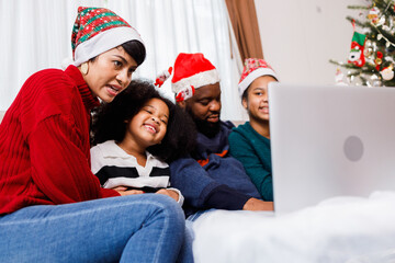 African American family have fun during video call on laptop and sitting together on the sofa at home. cheerful young family with children laughing. African American family in Christmas theme