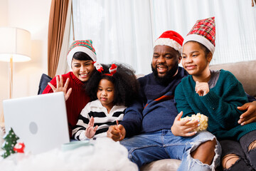 African American family have fun during video call on laptop and sitting together on the sofa at home. cheerful young family with children laughing. African American family in Christmas theme