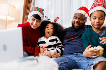 African American family have fun during video call on laptop and sitting together on the sofa at home. cheerful young family with children laughing. African American family in Christmas theme