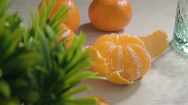 Dolly shot blurred green plant to mandarin fruit displayed on white table - Nutrition concept