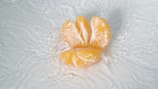 Slow motion peeled tangerine to fall into water surface, Fresh fruit Concept