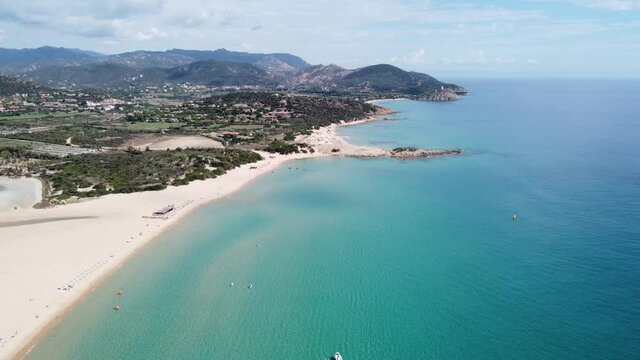 drone flight over the white sandy beach with crystal clear water in the bay of chia (sardinia), sunny!