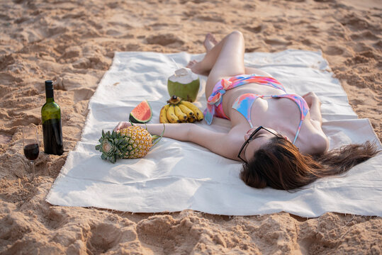 Asian beauties wearing bikini laying sunbathing on the beautiful sandy beach on vacation.Summer Holiday and travel concept.
