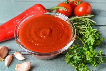 Bowl with organic tomato sauce and ingredients on table