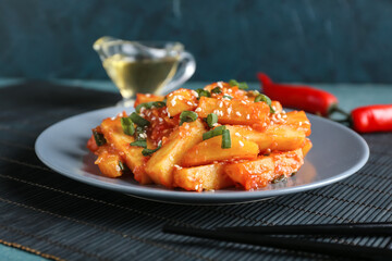 Plate with honey chilli potato and chopsticks on table