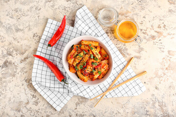 Bowl with honey chilli potato and chopsticks on grunge background