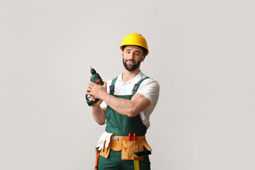 Construction worker with screw gun on light background